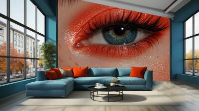 Close-up of a model's eye showcasing vibrant orange eyeshadow and sparkling skin tones Wall mural