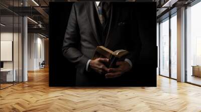 Man in suit holding a bible in his arm on a black background. AI generated Wall mural