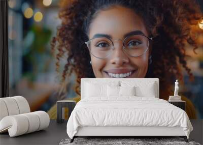 A cheerful young woman with curly hair enjoys a friendly conversation during a video call Wall mural