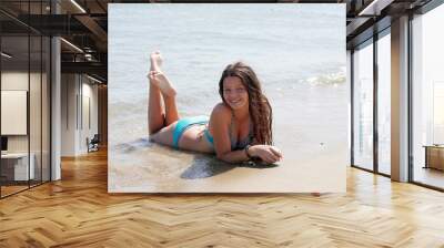 A girl in a blue bathing suit lying on beach Wall mural