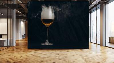 a glass of white wine on a black background. the smoke from the hookah envelops the glass. rest, holiday. alcoholic drink closeup. white fog in a glass. fog Wall mural