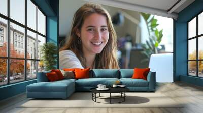 a young smiling caucasian woman is working at a laptop Wall mural