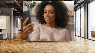 African American woman smiling carefree girl ethnic female lady homeowner on sofa talk video call smartphone chatting distant communication with mobile phone at home apartment positive virtual meeting Wall mural