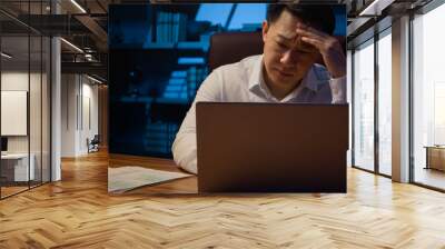 Asian stressed tired Korean man middle-aged exhausted overworked businessman laptop working problem paperwork business trouble bad result documents failure difficulties stress at night evening office Wall mural