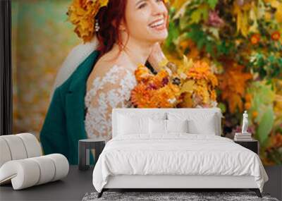 Beautiful bride in a wreath of maple leaves sitting near the wedding arch. Wall mural