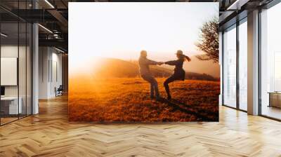 Beautiful couple circling holding hands enjoying each other at sunset. Holidays in the mountains. Wall mural