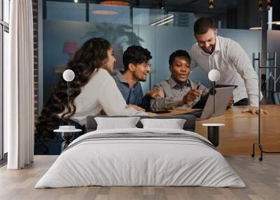 Business partners multiracial team group people workers in office looking at laptop happy with internet work success project opportunity multinational colleagues smiling receive notification offer Wall mural