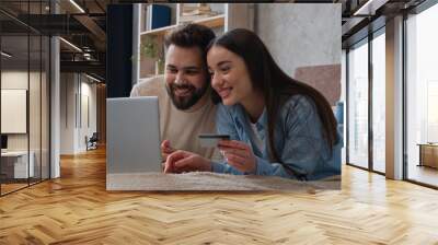 Caucasian couple happy woman and man looking at laptop screen on home bed excited smiling wife and husband pay money online use bank credit card family budget e-commerce buy goods shopping for bedroom Wall mural