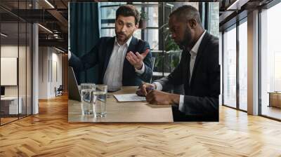 Caucasian manager showing African boss bad business result computer mistake two diverse men multiracial coworkers businessmen with papers and laptop sad upset failure discuss startup problem at office Wall mural