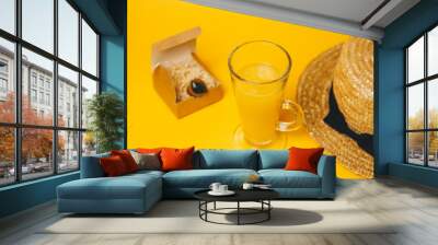 concept of relaxation and thirst on the beach. a glass of lemonade on a yellow background with a straw hat. top view Wall mural