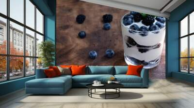 Cottage cheese dessert with blueberries, blackberries and mint in a transparent glass glass. On a wooden background. Yummy. Wall mural