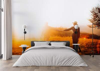 Full side view. Happy couple holding hands enjoying each other at sunset. Travel in the mountains. Wall mural