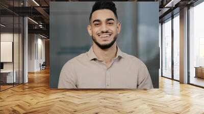 Happy young guy hispanic handsome man with toothy smile looking at camera male face portrait businessman smiling arab professional manager entrepreneur posing positive in modern office close up view Wall mural