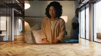 Scared afraid sad upset frustrated victim African American woman wife girlfriend separated apart from angry mad screaming shouting blame man husband boyfriend couple conflict in bed domestic violence Wall mural