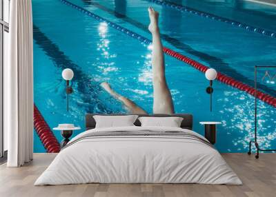 synchronized swimming athlete trains alone in the swimming pool. Training in the water upside down. Legs peek out of the water. sports figure from legs Wall mural