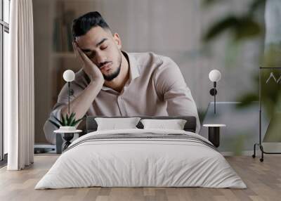 Tired sleepy hispanic man arab guy dreaming overworked male student slumber at office laying down on desk leisure close eyes napping feel exhausted falling asleep has chronic insomnia health problem Wall mural