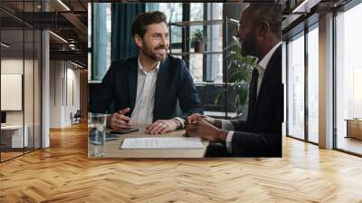 Two diverse businessmen Caucasian man and African American businessman with laptop computer in office corporation company talking discuss online result business strategy marketing planning laughing Wall mural