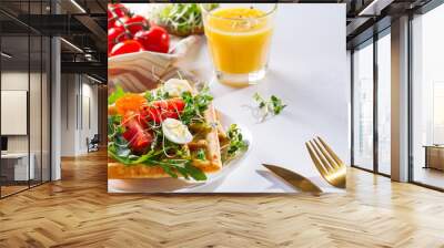 Fresh baked sweet belgian waffles with eggs, tomatoes, micro green and avocado served on a plate with orange juice on marble table. Healthy breakfast Wall mural