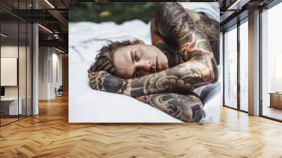 Young handsome tattooed man laying in bed in the open air outdoors in the garden. Wall mural