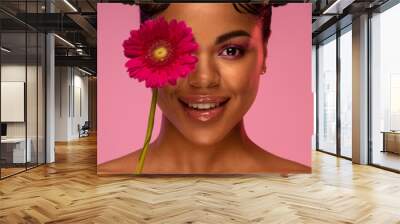 Close-up portrait of a young woman for beauty salons: makeup, radiant skin, beautiful lips. On a pink background with a pink flower Wall mural