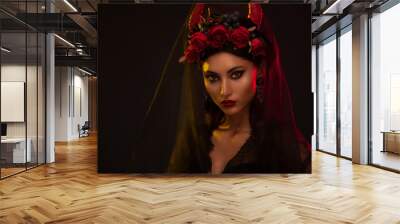 Creative image of Halloween makeup look or Dia De Los Muertos holiday on dark background with copyspace. Beautiful Model with dark hear wearing a headpiece with red horns and red flowers Wall mural