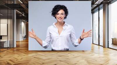 Happy Young brunette Businesswoman curly Hair on Gray Background with Copy Space Looking at the Camera with open arms Wall mural