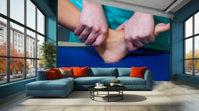 The patient girl is in the office of the doctor osteopath. A practicing physician treats the joints of the legs and back with manual therapy. Wall mural