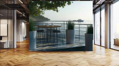 A table with two cups and a potted plant is on a pier overlooking the ocean Wall mural