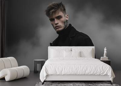 Male model with short hair, dressed in all black, tattoos visible, exuding a rebellious aura in a fog-covered setting Wall mural