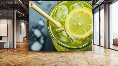 Close up of a glass of green drink with lemon and ice with a straw. Wall mural