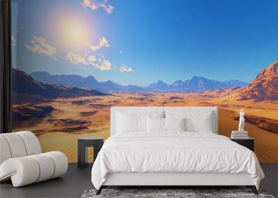 Desert landscape with sand dunes and mountains under a blue sky with the sun shining. Wall mural