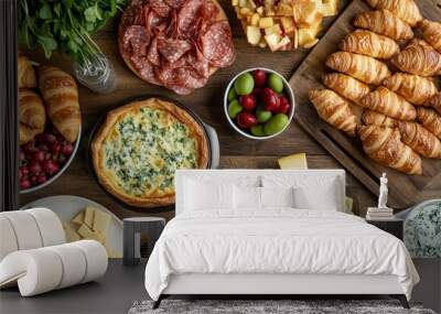 French pastry, croissants, quiche, cheese, salami, fruits, and greens served on a rustic wooden table. Wall mural