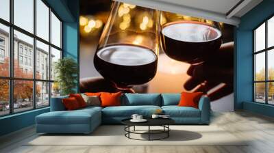 Two glasses of wine  red in hand on the background candle and  garlands  Wall mural