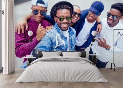 a group of five fashionable cool African American guys students communicating on the street looking at smartphone take pictures selfie on phone in street Wall mural