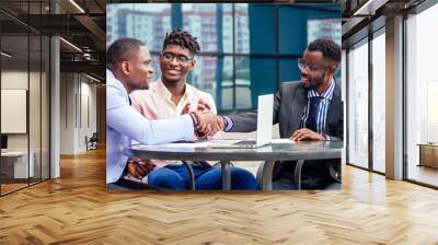 A group of three stylish African American businessman friends entrepreneurs fashion business suits meeting sitting at table and handshaking in a summer cafe outdoors. concept of successful good deal Wall mural