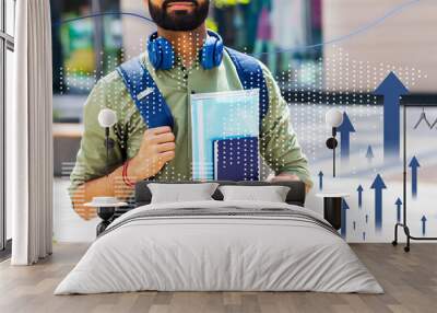 A man wearing a green shirt and blue backpack is holding two books Wall mural