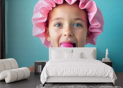 A young girl is holding a pink lollipop and wearing a pink hat Wall mural