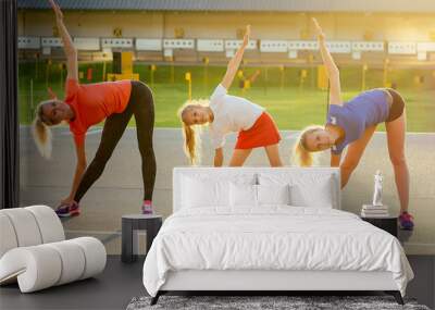 active family at outdoor. two blonde woman twin sisters and their daughters in stylish sportswear warm up and do exercises crossfit and fitness in the stadium . group of four girls in the park Wall mural