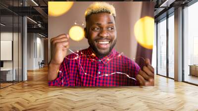 african man making preparations for Christmas party and decorating home with glowing garland Wall mural