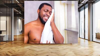 afro american male wiping his face with cotton napkin at home Wall mural