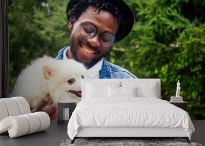 afro man hugging his fluffy spitz in park Wall mural