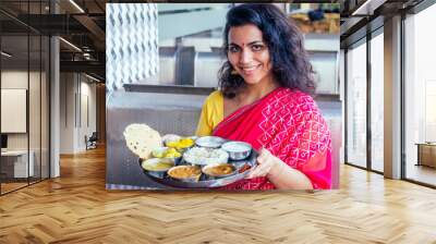 beautiful brunette woman in red sari eating with appetite traditional thali wirh rise,curd,dal in Goa restaurant masala tea Wall mural