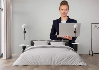 Business woman in a stylish black a jacket suit with a laptop in the studio on a white background Wall mural