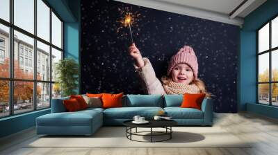 charming little girl in a knitted pink hat holding fireworks on black background in a studio.Cute blonde child with xmas dream.Happy kid enjoy the fire sparks. new year holidays eve of Christmas wish Wall mural