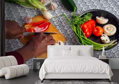 closeup of man hands african american cuts vegetables fry salad pepper, mushrooms, tomato in kitchen recipe book on the table .vegan healthy food Wall mural