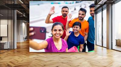 four indian people warming up outdoors in sport wear making selfie on smartphone camera Wall mural