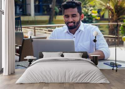 indian businessman working on tablet computer copyspace on tropical beach cafe.freelancer man in a white shirt collar surfing online sale success and freedom Wall mural