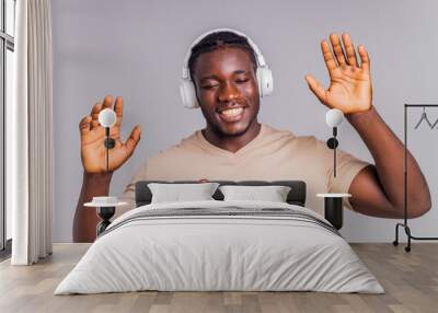 mexican man with white headphone listening music in beige t-shirt Wall mural