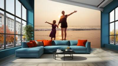 mothers Day concept of love, parenthood and a happy family. Mother and child daughter having fun at sunset on beach Wall mural