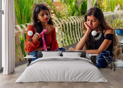 sad fashionable indian friends couple of two woman looking at cakes.friends long-awaited meeting gossip students eating pancake drinking masala tea after shopping.summer instahram lifestyle Wall mural